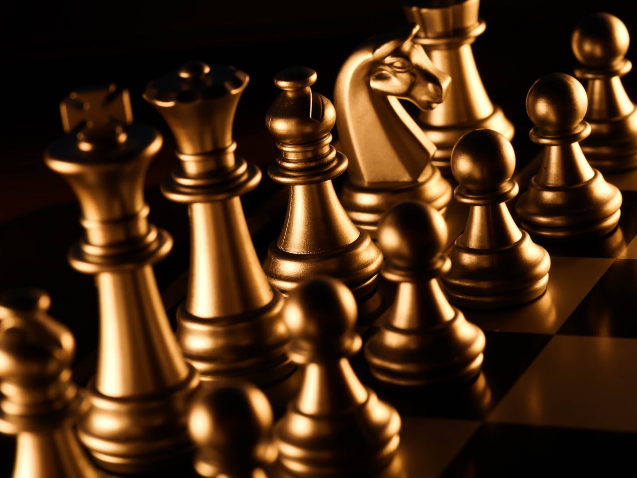 Close-up of shiny golden chess pieces on a checkered board. Symbolizes strategy and intelligence.